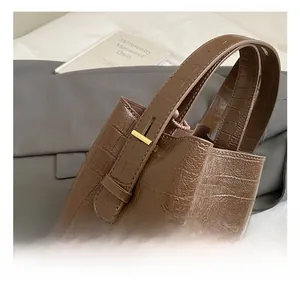 Close-up of brown crocodile texture bucket bag with premium gold metal hardware buckles