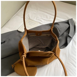 Detail of the caramel tote bag showing striped lining, inner pocket, and magnetic clasp