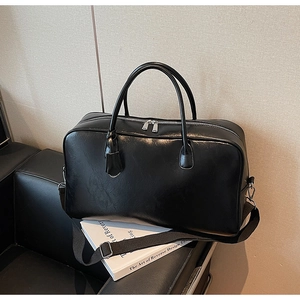 Détail du sac Boston en cuir noir montrant la texture lisse et les fermetures éclair argentées