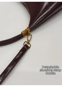 Detail of glossy burgundy leather bag featuring a vintage gold detachable strap buckle