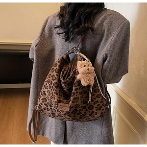 Detail of leopard print tote bag with brown leather strap and plush bear charm