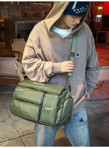 Detail showing the army green nylon multi-pocket travel bag worn by a model in city street