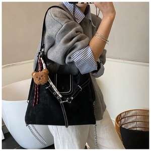 Detail of black matte tote bag featuring contrast stitching, metal chain, and bear charm