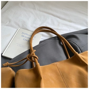Detail shot of caramel tote bag with knotted handles and matching small pouch