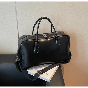 Détail d'un sac de voyage en cuir PU brillant noir avec poignées solides et métal