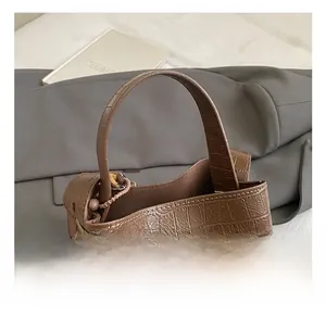 Detail shot of the wide carry handle and dark brown crocodile embossed leather texture