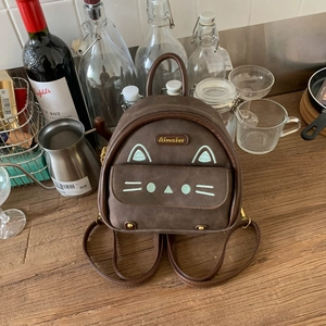 Brown faux suede mini backpack with cat embroidery in a cozy lifestyle setting
