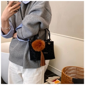 Détail du sac à main noir léopard avec pompon en fourrure marron et breloque à franges