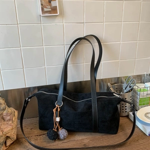 Detalle del bolso bandolera de ante negro con pompón esponjoso y cremallera metálica