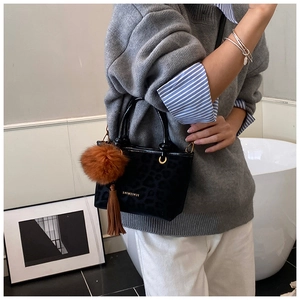 Détail du sac seau noir léopard avec pompon marron et glands décoratifs en cuir