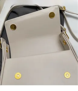 Detail of cream flap bag showing dual gold magnetic metal closures in open state
