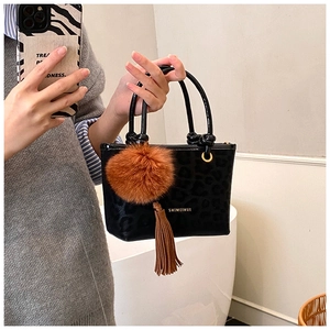 Détail du sac seau léopard noir avec logo doré et breloque en boule de fourrure marron