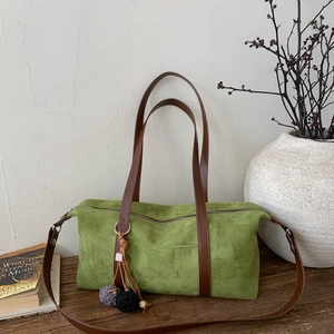 Detalle de bolso Boston verde mate con correas de cuero marrón y borla trenzada