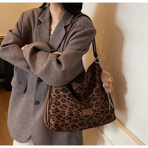 Detail of leopard print tote bag with brown leather strap and plush bear charm