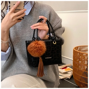 Détail du sac seau noir en cuir verni léopard avec pompon en fourrure et pampille
