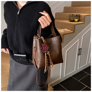 Close-up of a dark brown crocodile texture bucket bag with a leopard bear charm