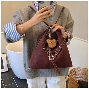 Close-up of vintage burgundy tote bag featuring white stitching and cute bear charm detail