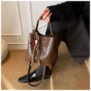 Detailed shot of brown crocodile pattern bucket bag with a cute leopard bear charm