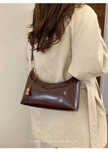 Detail of a vintage dark brown glossy leather underarm bag with gold chain and strap