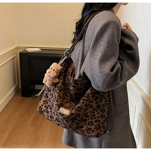 Detail of leopard print hobo bag featuring a plush bear charm and adjustable leather strap