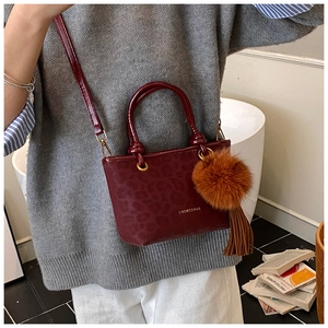 Détail du sac seau léopard avec pompon en fourrure marron et finitions à longues franges