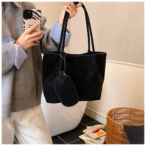Detail of black tote bag with white contrast stitching and a small matching pouch pendant
