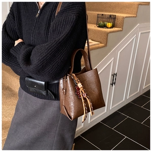 Detail of vintage brown stone pattern bucket bag with decorative tassel and bead charm
