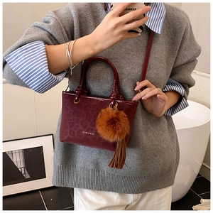 Détail du sac seau bordeaux à motif léopard avec pompon en peluche et breloque