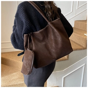 Close-up of vintage brown tote bag with decorative stitching and detachable mini pouch