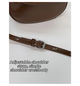 Detail view of adjustable leather strap with silver buckle on a brown saddle bag