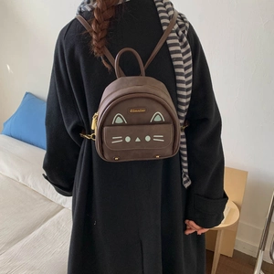 Detailed back view of a brown suede cat-themed mini backpack on a person's shoulder