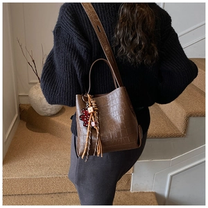 Brown crocodile texture bucket bag with heart bear charm shown as crossbody on model