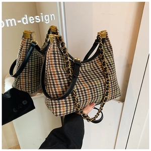 Detailed shot of checkered tweed texture and golden chain strap on shoulder bag