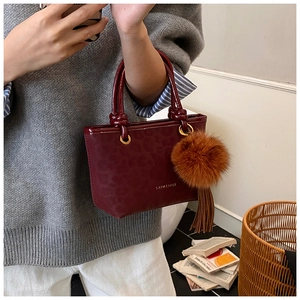 Détail du sac seau bordeaux avec gaufrage léopard et breloque pompon en peluche doux