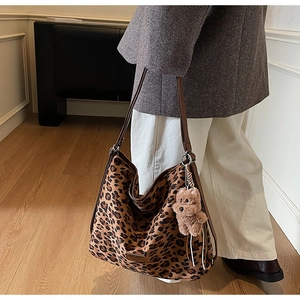 Detailed view of leopard print hobo bag with leather straps and plush bear charm