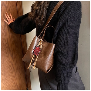 Detail of vintage brown crocodile texture bucket bag with leopard heart bear charm