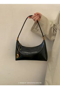 Detail of black hobo bag with smooth leather texture and gold water drop pendant charm