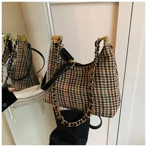 Detail of checkered shoulder bag with leather piping and decorative gold chain