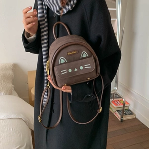 Detail of a brown suede cat backpack shown with a model in an elegant winter wool coat