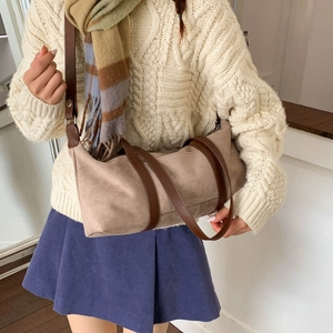 Detalle de un bolso cilíndrico retro mate combinado con un suéter y falda de pana