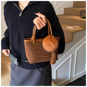 Détail du sac cabas léopard avec pompon en fourrure marron et accessoire à franges
