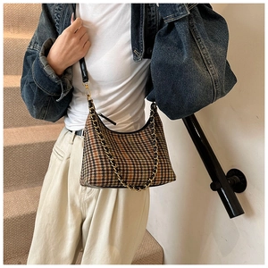 Detail of vintage brown houndstooth shoulder bag with gold chain strap and black leather trim