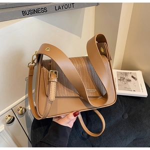 Close-up of tan synthetic leather handbag with woven texture flap and golden buckle