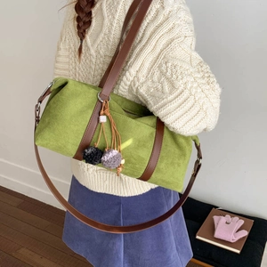 Detalle del bolso cilíndrico de ante verde lima con colgante de felpa y correas de cuero