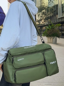 Outdoor shot of dark green multi-pocket travel bag with adjustable nylon shoulder strap
