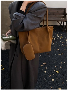 Detail of brown leather tote bag with a small zip pouch and minimalist vertical stitching