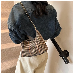 Detail of vintage plaid hobo bag with gold chain strap on model in indoor setting
