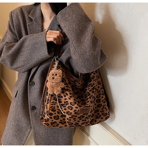 Detail of large leopard print hobo bag with leather trim and brown plush bear charm
