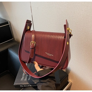 Detailed view of woven texture and golden text on a burgundy underarm leather bag