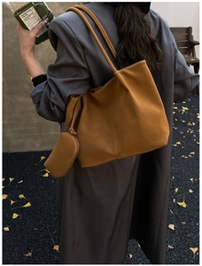 Detailed view of brown leather tote bag with small zipper pouch in outdoor autumn setting